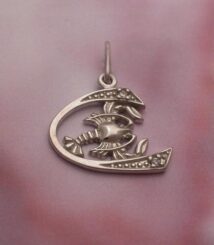 Silver crescent moon pendant with a lobster motif and dotted accents on pink fabric background