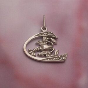 Silver crescent moon pendant with a lobster motif and dotted accents on pink fabric background