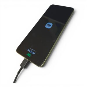 Smartphone screen shows a blue Mi logo, Android badge at bottom, connected to a charger via USB-C cable.