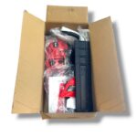 Open shipping box containing a red power tool, black storage module, and assorted accessories in plastic bags.