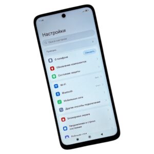 Смартфон в наклонной позе показывает экран русских настроек: поиск настроек и список пунктов (О телефоне, Wi‑Fi, Bluetooth)