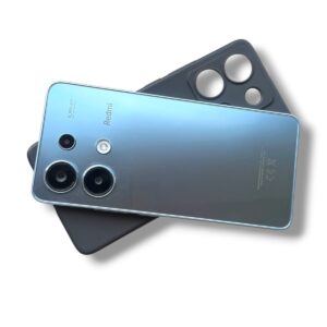 Blue Redmi smartphone back with a triple-camera system and flash, resting on a dark phone case on a white background?