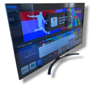 Curved flat-screen TV on a curved stand, displaying a colorful smart TV home screen with app icons and a streaming banner.