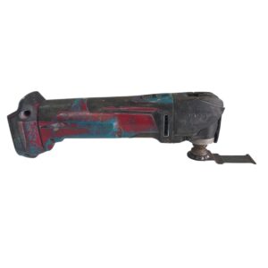 Well-worn cordless oscillating multi-tool with red, blue paint and a metal attachment on the right side