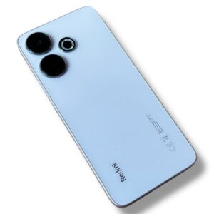 Back view of a light-blue Redmi smartphone showing three circular camera lenses and logo on the bottom edge.