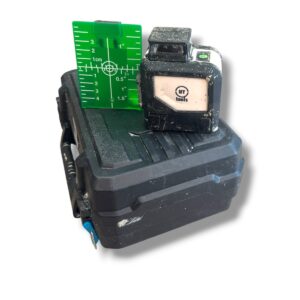 Cordless tool battery with a green measuring ruler resting on top, showing inch and centimeter marks.