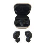 Open beige charging case with two black wireless earbuds inside; two extra earbuds placed below.