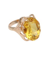 Gold ring with a large yellow, faceted gemstone set in an ornate prong setting.