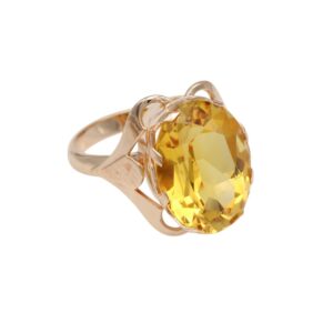 Gold ring with a large yellow, faceted gemstone set in an ornate prong setting.