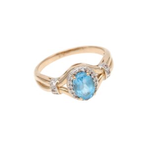 Gold ring with an oval blue gemstone surrounded by a halo of small diamonds on a split shank band.
