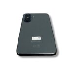 Back view of a Samsung smartphone with a triple camera module in the top-left corner and the Samsung logo visible on a gray/greenish back panel