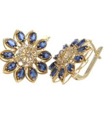 Gold-tone flower-shaped earrings with blue teardrop stones arranged around a jeweled center, clip-on backs, elegant jewelry accessory.