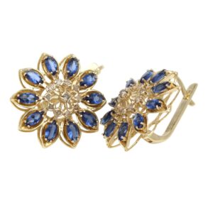 Gold-tone flower-shaped earrings with blue teardrop stones arranged around a jeweled center, clip-on backs, elegant jewelry accessory.