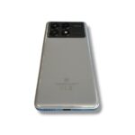 Back of a silver POCO smartphone with a quad-camera module and 5G emblem visible on the top left area of the camera panel.