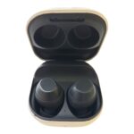 Open beige charging case with two black wireless earbuds inside.