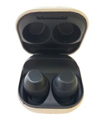 Open beige charging case with two black wireless earbuds inside.