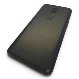 Back of a black OnePlus phone with a dual-camera module and scratches, placed on a white surface.