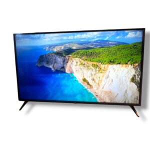 Flat-screen TV tilted on a stand displaying a blue ocean, rocky cliffs, and green hills nearby.