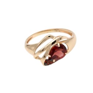 Gold ring with twisted, intertwining bands and a red oval gemstone centerpiece, set in a decorative bezel.