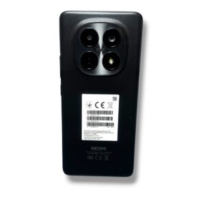 Back view of a black Redmi smartphone showing a square quad-camera module and a sticker on the back.