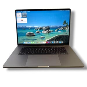 Open MacBook Pro displaying a blue coastal wallpaper with rocks and ocean, on a silver keyboard setup against a white background.