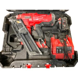 Red cordless drill with batteries and charger inside a black toolbox tray.