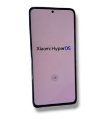 Back of a black Redmi smartphone with a triple-camera cluster and flash near the top-left corner