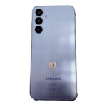Blue Samsung smartphone back with a vertical triple-camera array in the top-left corner and a subtle dotted texture.
