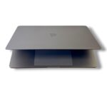 Two thin silver laptops stacked, top lid closed with a faint Apple logo visible