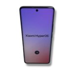 Xiaomi smartphone displaying HyperOS branding on a purple-pink gradient screen with a circular forward-arrow button at the bottom left/right area.