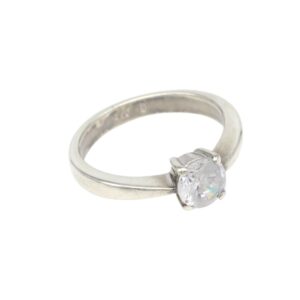 Silver ring with a single round brilliant-cut diamond held by four prongs, shown in a side angle against a white background.