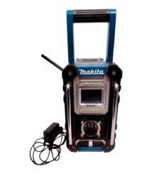 Makita portable job-site radio with Bluetooth, blue and black, carrying handle and power adapter nearby.