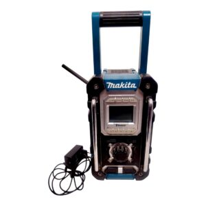 Makita portable job-site radio with Bluetooth, blue and black, carrying handle and power adapter nearby.