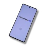 Tilted smartphone showing the Xiaomi HyperOS startup screen on a lavender background.