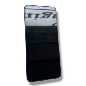 Black smartphone tilted diagonally, screen off and reflecting a blurred sign in the surroundings.