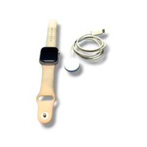 Beige smartwatch with a magnetic charging puck and a white USB charging cable beside it on a white background