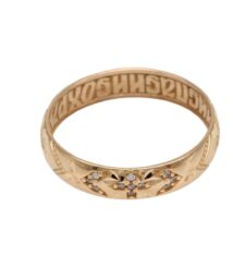 Gold ring with intricate engraved pattern and small diamonds set on the front, viewed at an angle