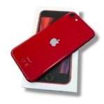 Red iPhone with white Apple logo resting on its white box, angled to show back and camera.