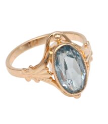 Gold ring with an oval pale-blue gemstone set in an ornate bezel and prongs.