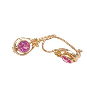 Gold drop earrings with a pink faceted gemstone in a circular frame and a small flower accent.