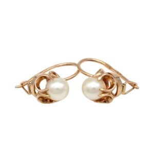 Gold earrings with round white pearls set in ornate gold hoops on a white background