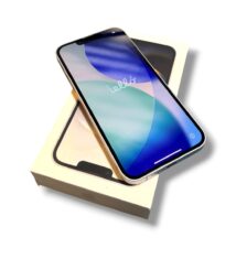 Smartphone with blue wallpaper resting diagonally on a light-colored box, angle showing rounded edges and screen glow