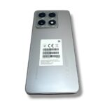 Back of a silver Xiaomi smartphone with a quad-camera module and a white barcode label on the center of the back area