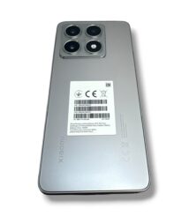 Back of a silver Xiaomi smartphone with a quad-camera module and a white barcode label on the center of the back area