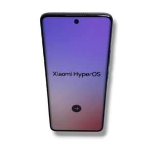 Phone screen shows 'Xiaomi HyperOS' on a purple‑pink gradient; front camera notch centered at top and a circular next-step button visible.