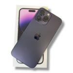 Dark blue iPhone with triple-camera back resting on its box, angled to show cameras and Apple logo on a white background.