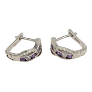 Pair of silver-toned curved hoop earrings with a row of purple and clear gemstones along the front on a white background