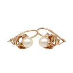 Gold earrings with round white pearls set in ornate openwork hoops on a white background