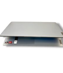 Slim silver Lenovo laptop partially open, exposing keyboard area with Ryzen stickers visible on the palm rest