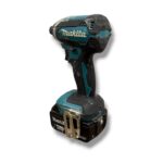 Makita cordless drill with 18V battery and belt clip, shown from the side, used and dusty.